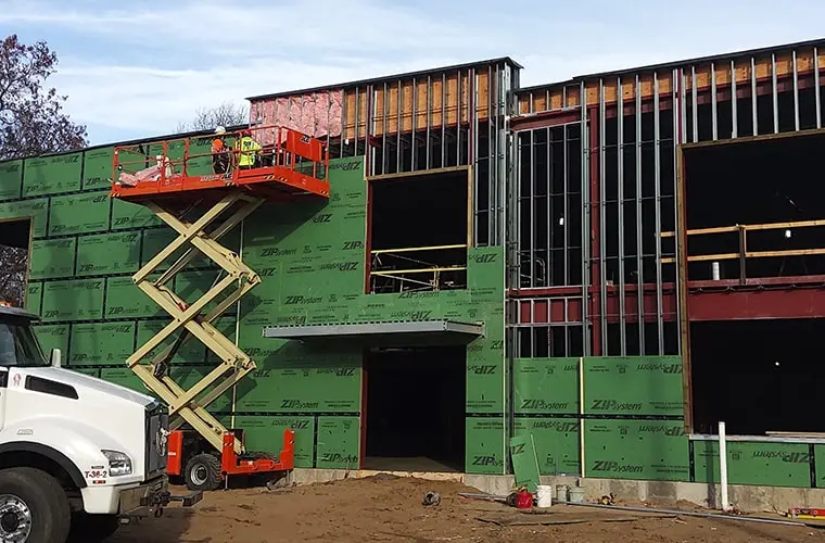 Workers on a lift installing insulation